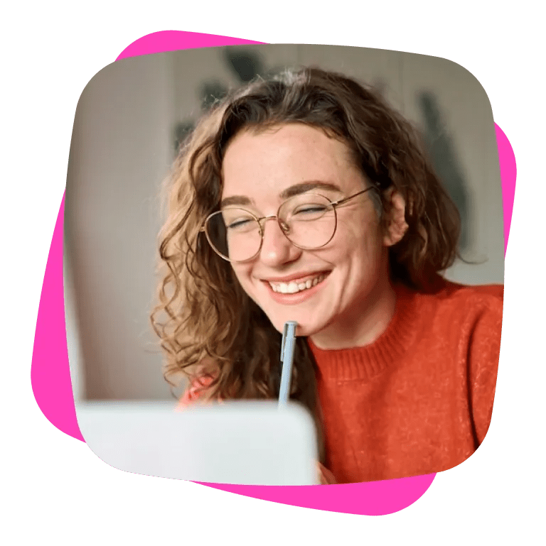 Cropped image of a smiling woman looking at her laptop with a pen resting on her chin